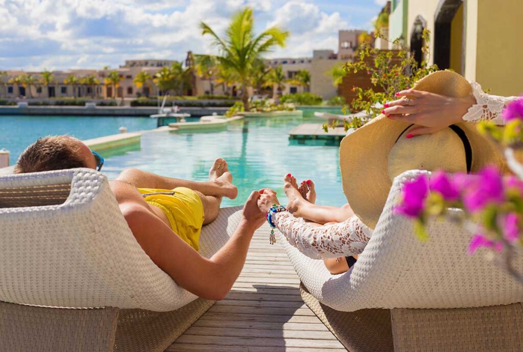 hotel guests sun bathing by luxury resort pool